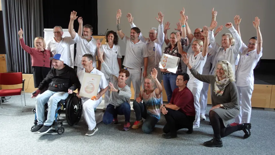 Gruppenfoto vom Team des AUVA-Rehabilitationszentrums Häring, das die Kinästhetik-Auszeichnungsurkunde präsentiert