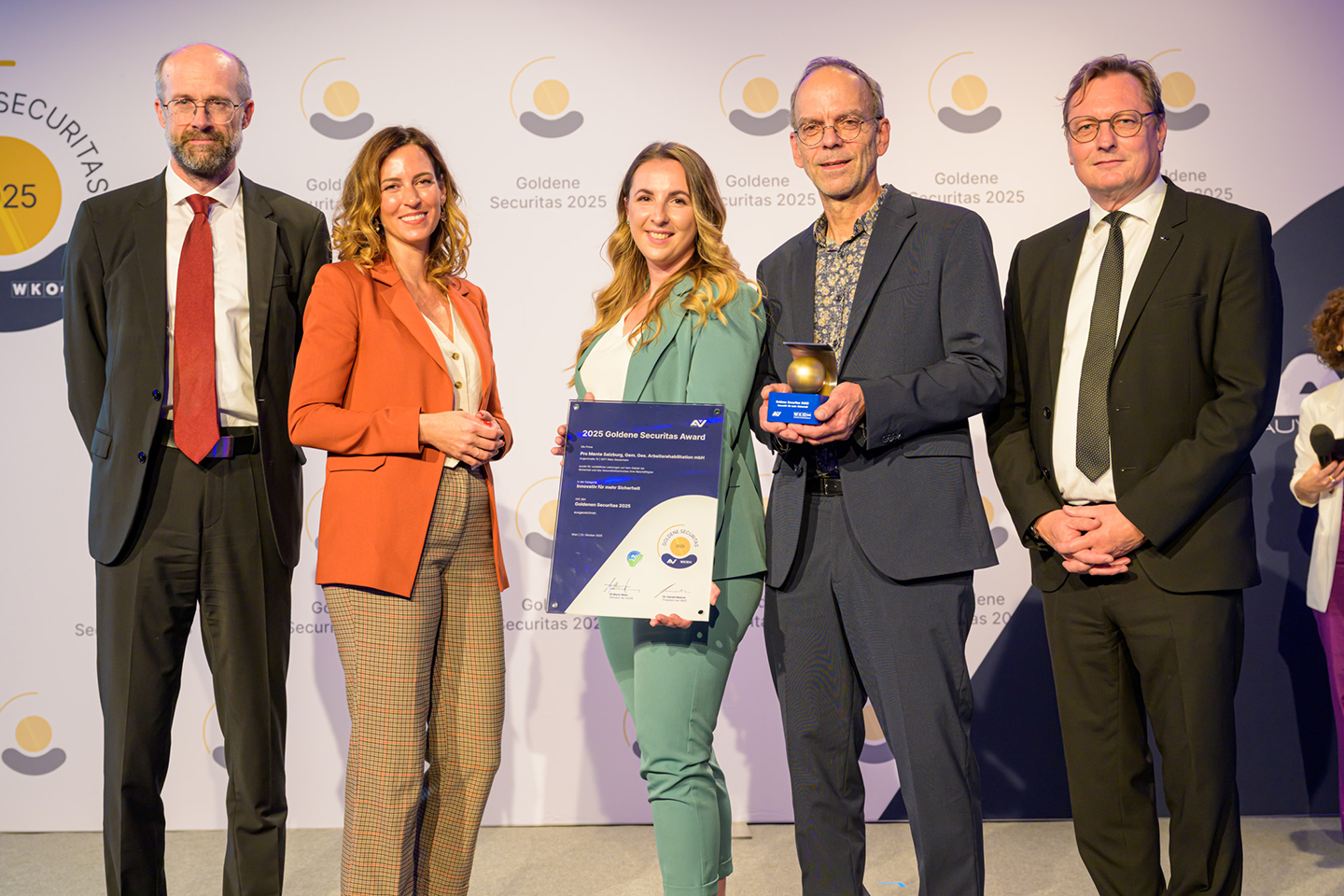 Eine Gruppe von Erwachsenen steht vor der Goldene Securitas-Logowand