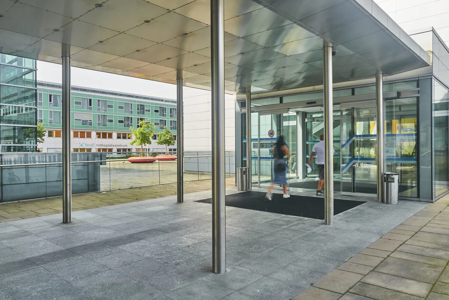 Zwei Personen betreten am Haupteingang des UKH Linz das Gebäude Zwei Personen betreten am Haupteingang des UKH Linz das Gebäude