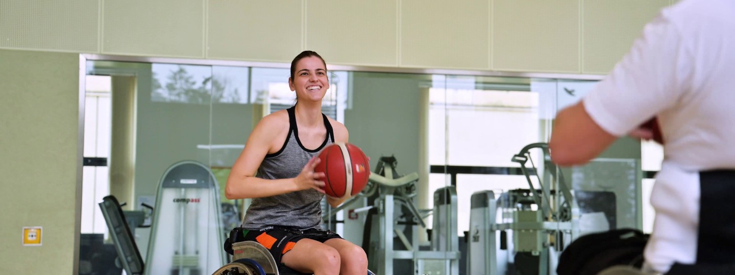 Rollstuhlbasketballerin Monika mitten im Spiel mit dem Basketball in der Hand