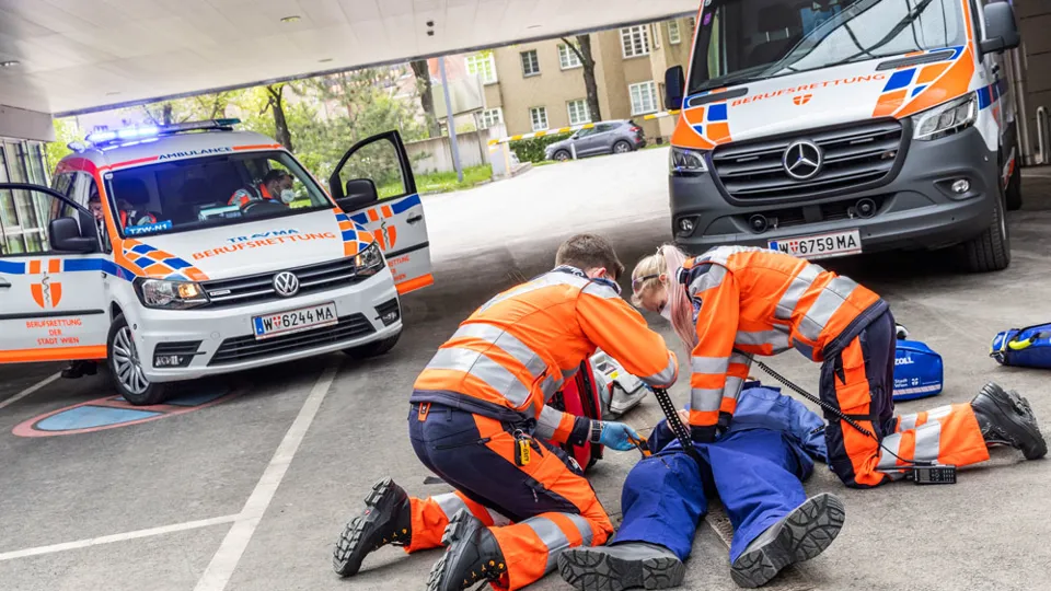 Sanitäter:in bei Einsatz-Übung mit Notarzt-Einsatz-Fahrzeug (NEF) im Hintergrund
