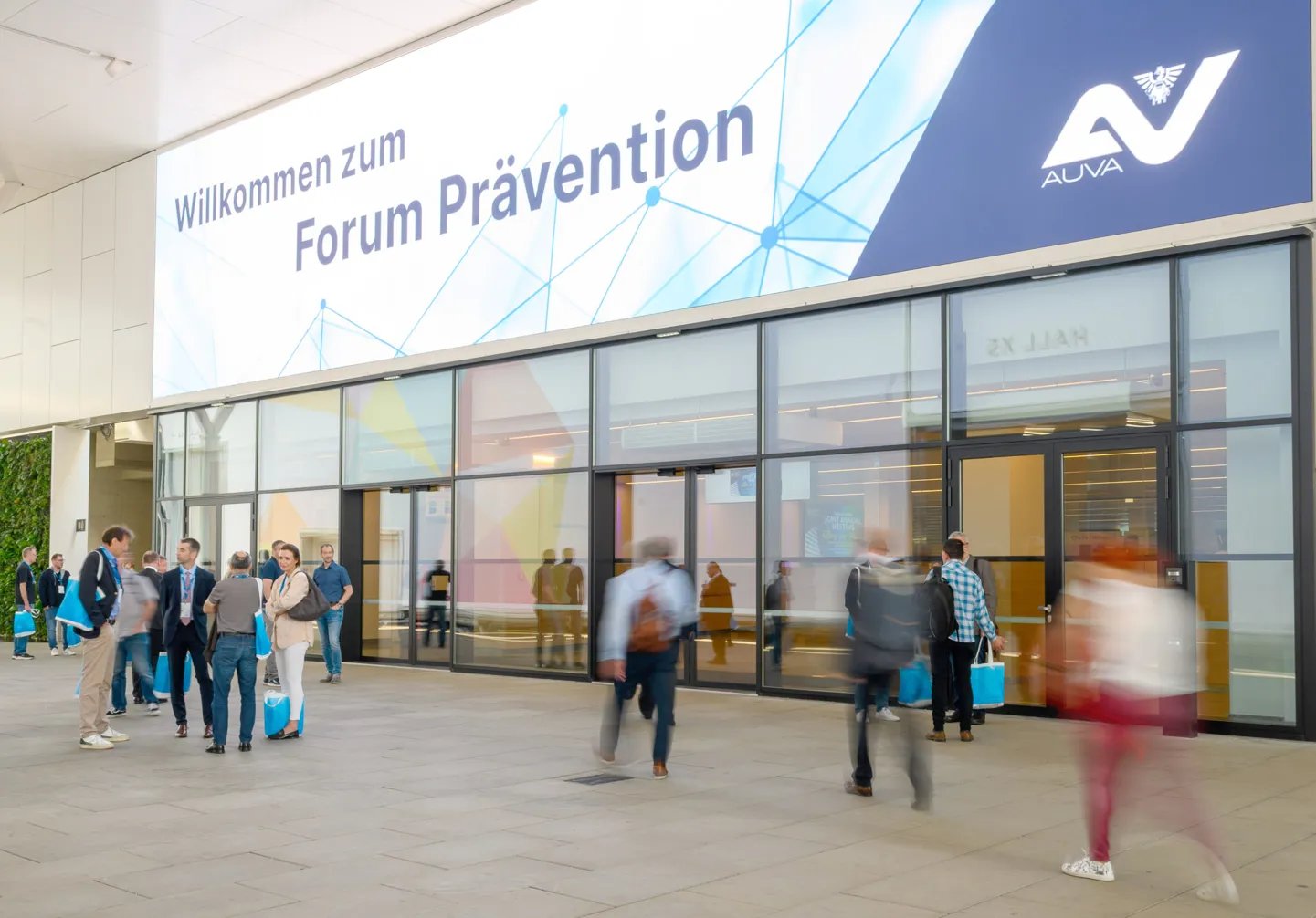 Mehrere Kongressbesucher halten sich vor dem Haupteingang zum internationalen AUVA-Kongress “Forum Prävention” auf.   