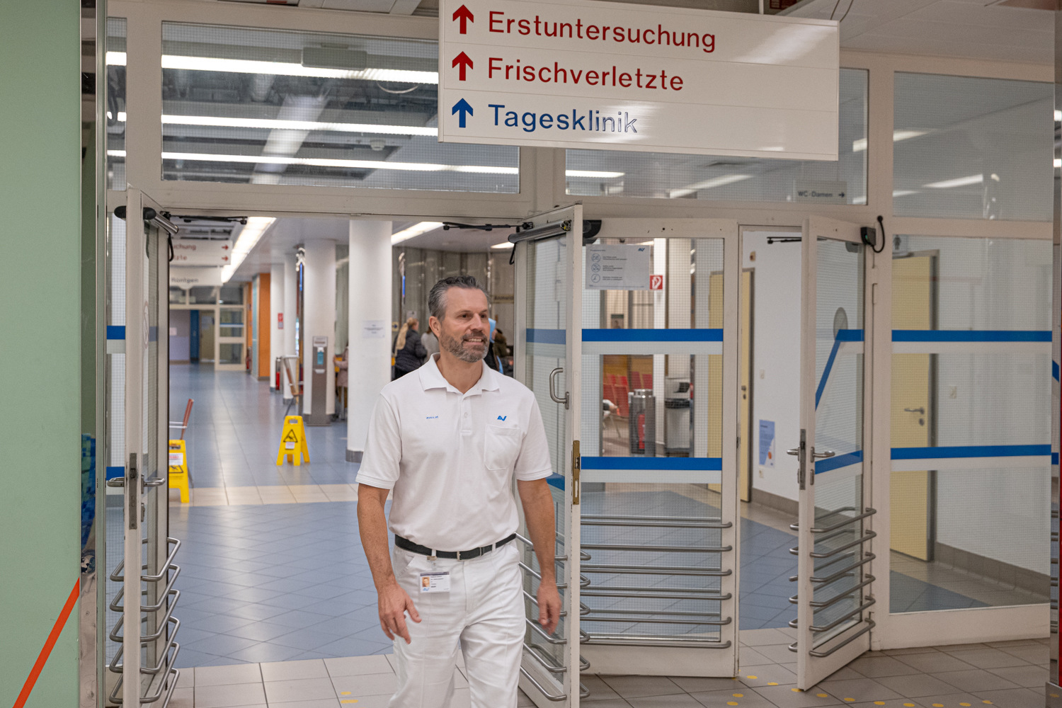 Prim. Dr. Thomas Beer geht durch einen Spitalsgang, über ihm sind Wegweiser u.a. zur Tagesklinik