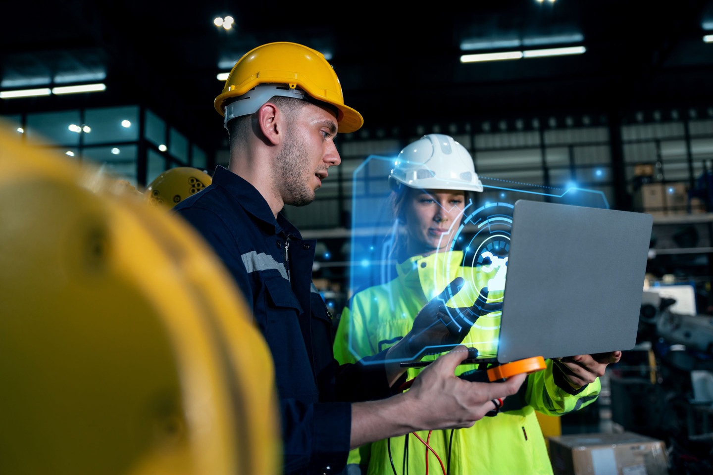Ein Mann und eine Frau stehen nebeneinander und blicken auf einen geöffneten Laptop. Davor erscheint eine KI-Projektion.