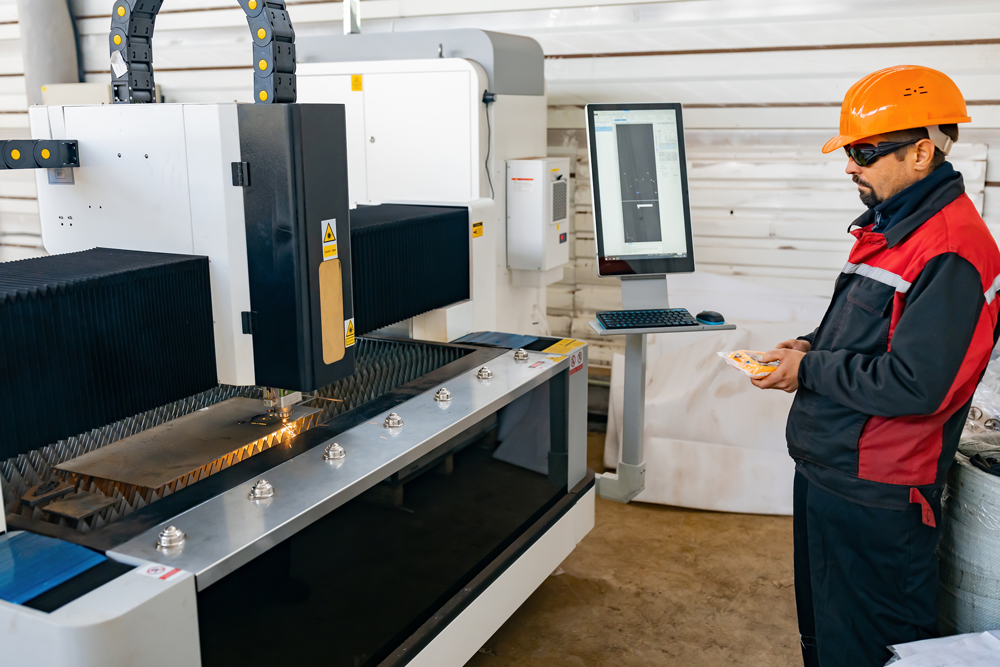 Arbeiter mit Laserschutzbrille bedient Metallverarbeitungsmaschine.