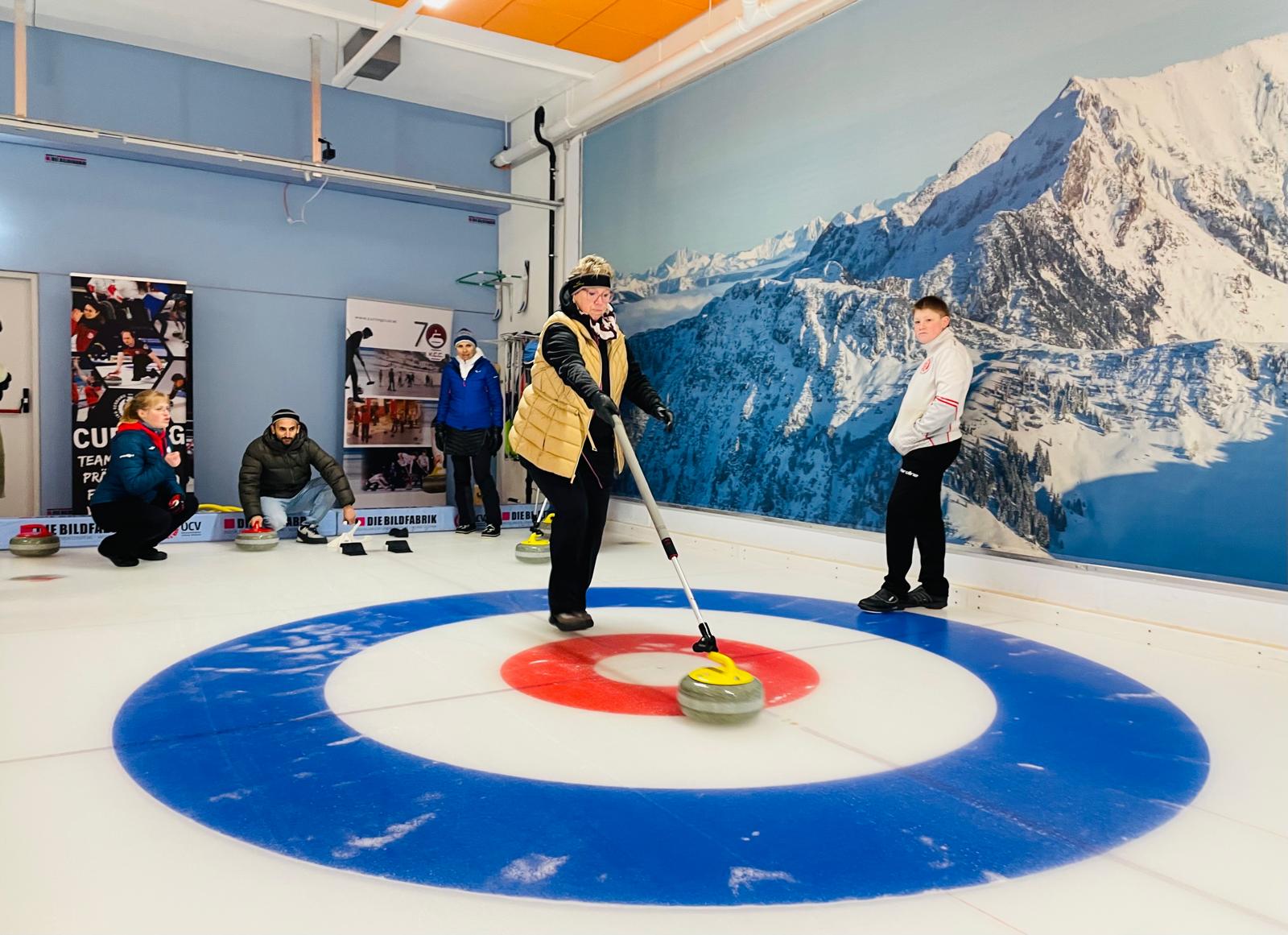 Eine Teilnehmerin in Aktion am Eis, im Hintergrund sind vier weitere Personen erkennbar. 