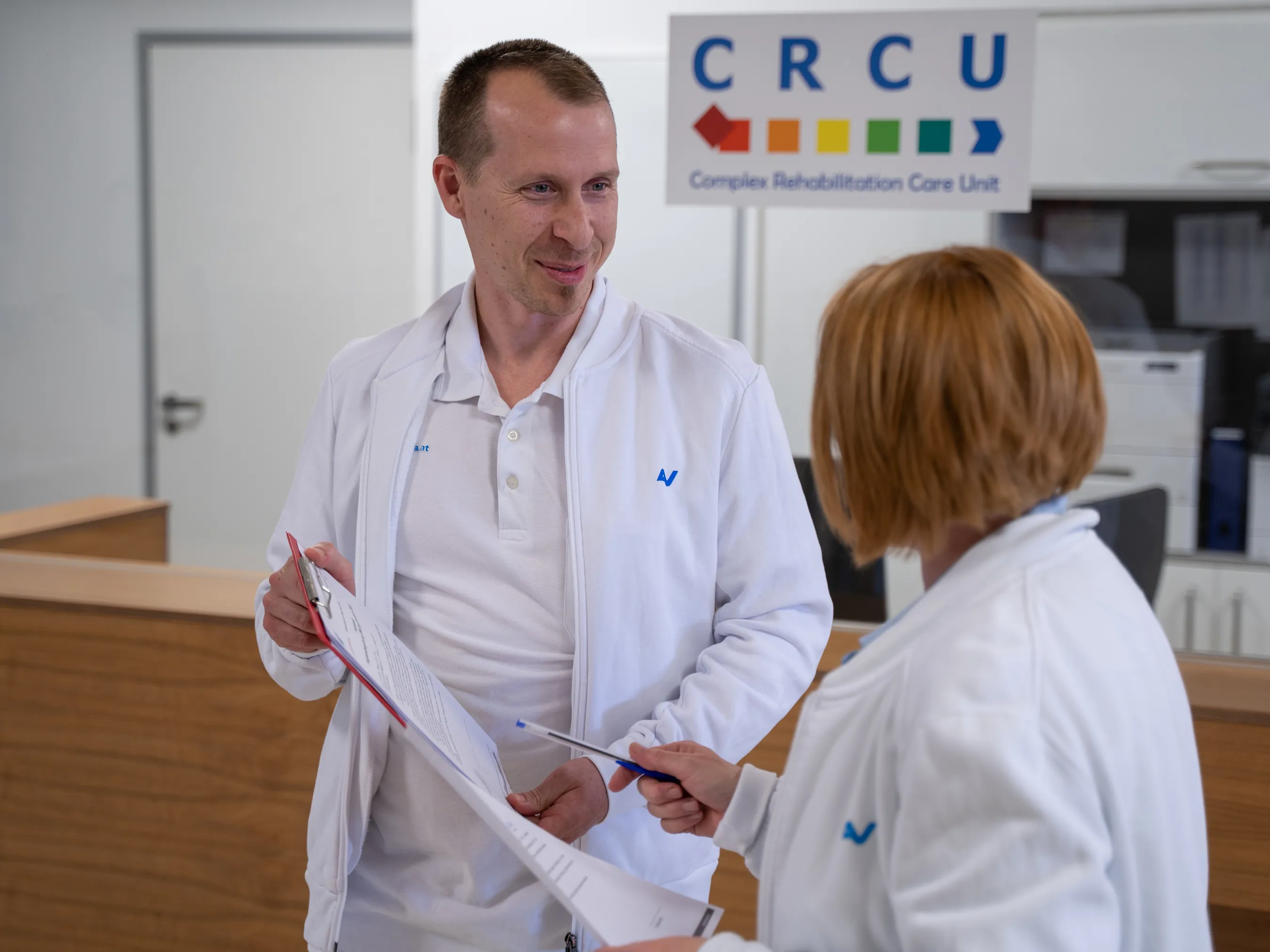 Ein Mitarbeiter und eine Mitarbeiterin der Complex Rehabilitation Care Unit im RZ Meidling führen eine unkomplizierte Besprechung. 