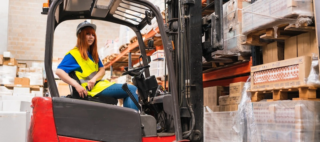 Junge Frau im Gabelstapler Junge Frau im Gabelstapler schnallt sich an.