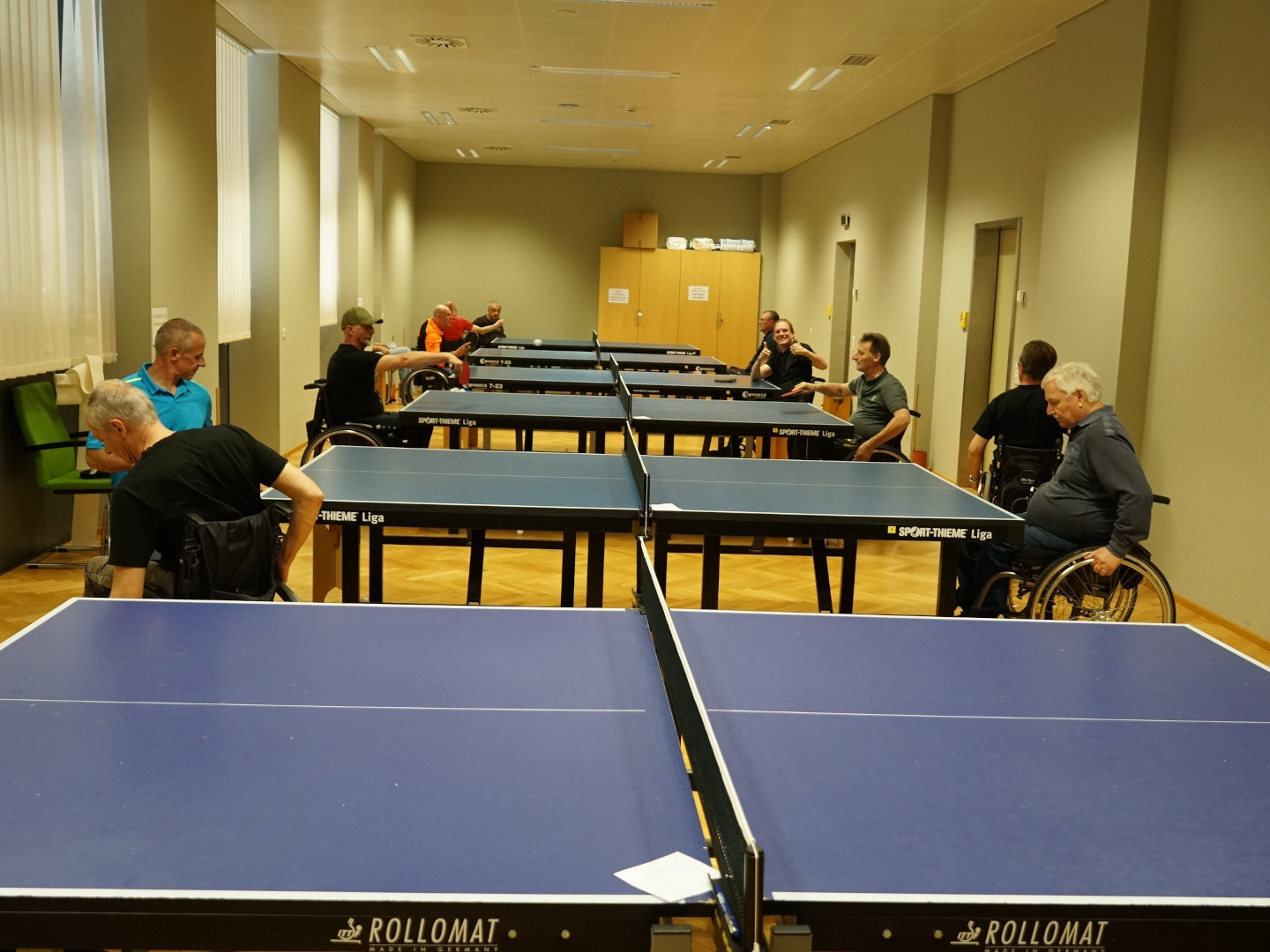 Teilnehmer des Turniers im Tischtennisspiel an mehreren Tischen