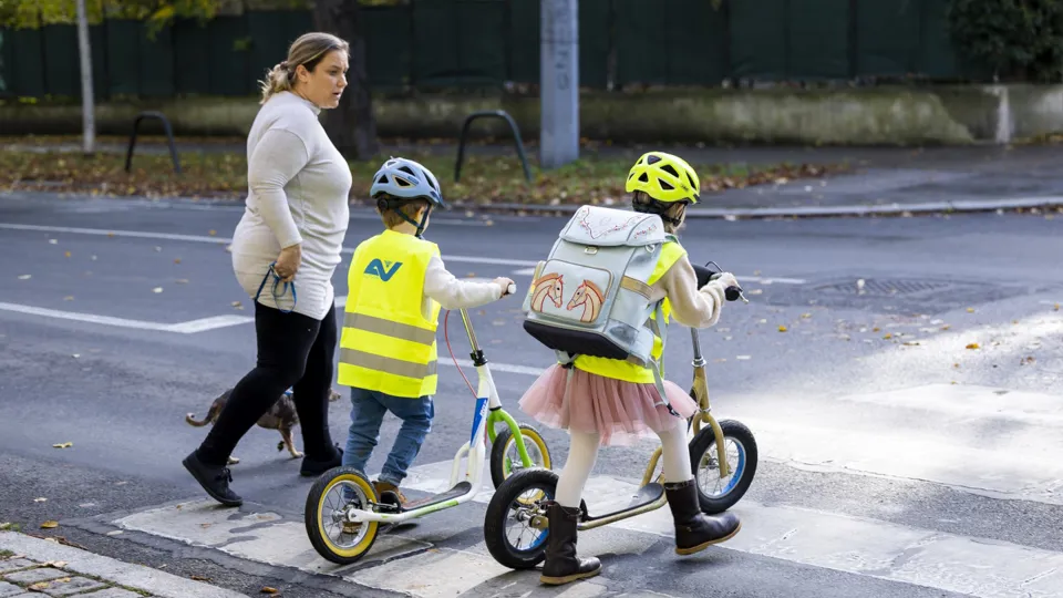 Roller Zebrastreifen 1440 Credit CAP Martin Steiger Eine Frau begleitet zwei Kinder am Tretroller über den Zebrastreifen