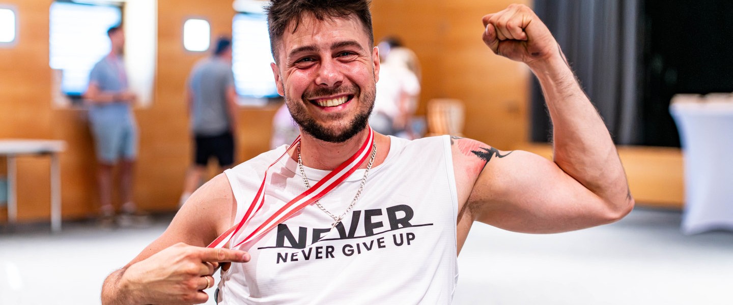 Sportler, der eine Medaille um den Hals trägt, ballt die Faust und lächelt 