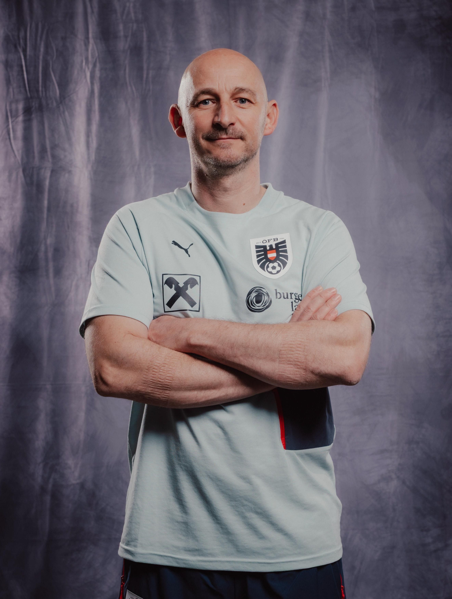 Bild von Dr. Michael Fiedler, der in ÖFB-Trainingskleidung mit verschränkten Armen vor der Kamera steht