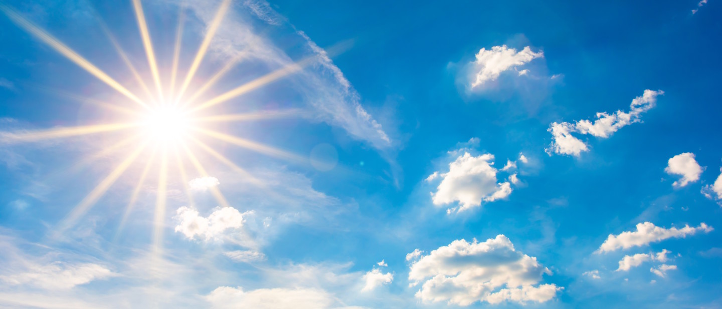 Himmel mit strahlender Sonne und weißen Wolken