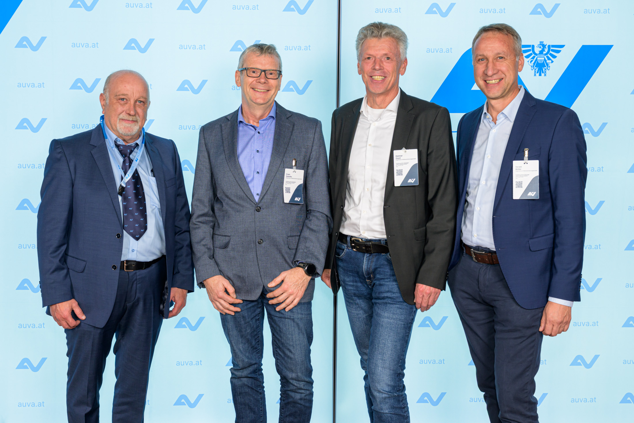 Vier Männer vor einer AUVA-Logowand