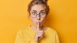 477955020 1440 Credit Wayhome.Studio Adobestock Junge Frau hält den Zeigefinger zur Schweigegeste vor den Mund