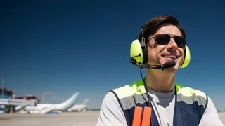 Adobestock 217902259 1440 ©Yakobchuk Olena Stock.Adobe.Com Mann mit Sonnenbrille und Headset schaut am Flughafen in die Sonne