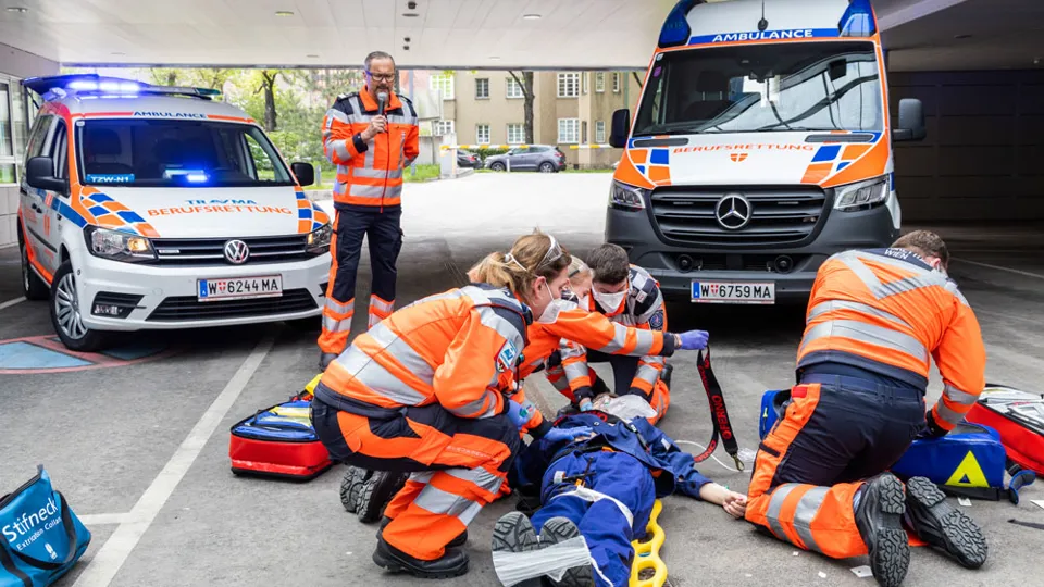 Sanitäter:innen bei Einsatz-Übung mit Notarzt-Einsatz-Fahrzeug (NEF) im Hintergrund